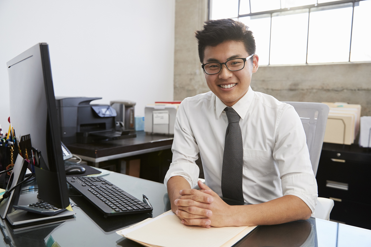 Young business professional at desk smiling to camera